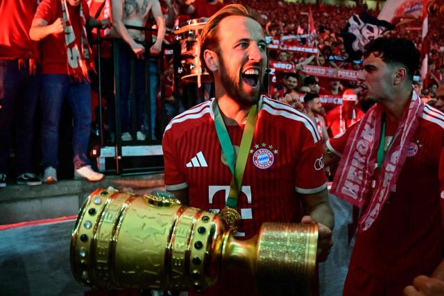 Bayern Munich's English forward #09 Harry Kane and his teammates celebrate with the trophy in front of their fans after the German Cup (DFB Pokal) final football match FC Bayern Munich v VfB Stuttgart at the Olympic Stadium in Berlin, on May 23, 2026. (Photo by Tobias SCHWARZ / AFP) / ALTERNATIVE CROP
