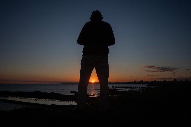 A man enjoys the view as the sun sets behind the Bay of Montevideo on May 23, 2026. (Photo by Eitan ABRAMOVICH / AFP)