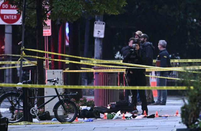 A forensic investigator takes photos behind a police tape blocking off a crime scene with evidence markers seen on a sidewalk on 17th and Pennsylvania Ave near the White House in Washington, DC, on May 23, 2026. Police and security forces swarmed the area around the White House on the evening of May 23 after reports of shots fired, AFP journalists said. US President Donald Trump was at the White House at the time as he worked to negotiate a deal with Iran. (Photo by Brendan SMIALOWSKI / AFP)