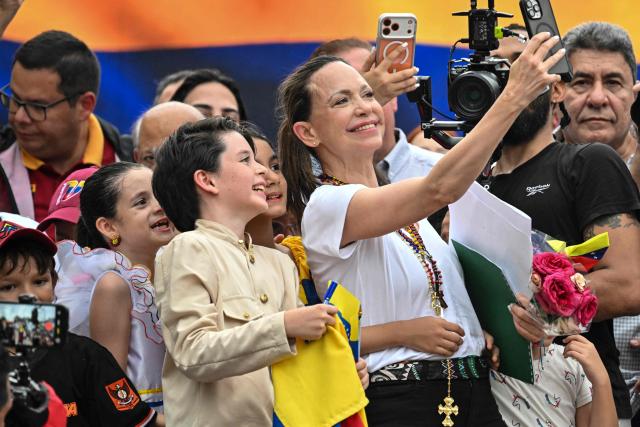 Venezuelan opposition leader Maria Corina Machado takes a selfie with children of the Venezuelan diaspora during a rally in Panama City on May 23, 2026. Machado is visiting Panama as part of a regional tour, during which she is set to meet with members of the Venezuelan diaspora and Panamanian President Jose Raul Mulino. (Photo by MARTIN BERNETTI / AFP)