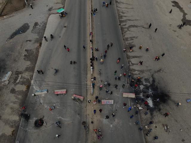 This aerial view shows demonstrators blocking a road during a protest against the government of Bolivian President Rodrigo Paz in El Alto, Bolivia, on May 23, 2026. The Bolivian government said it would deploy a police and military operation starting on the morning of May 23 to allow the passage of scarce goods into La Paz through roadblocks, as unions and Indigenous groups press their calls for President Rodrigo Paz to step down. (Photo by Marvin RECINOS / AFP)