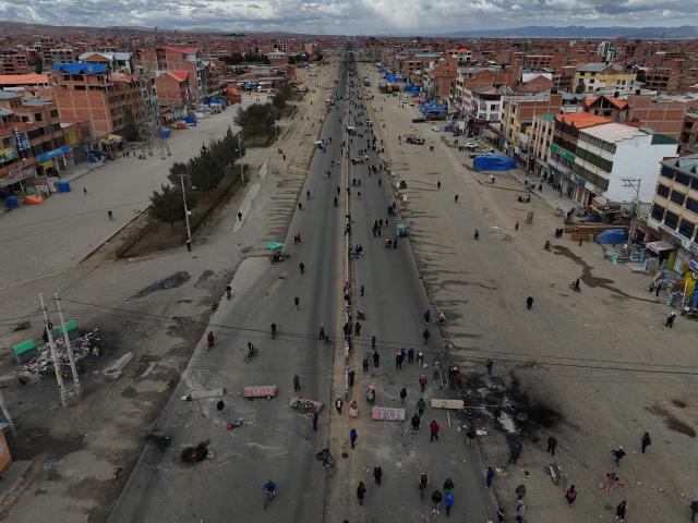 This aerial view shows demonstrators blocking a road during a protest against the government of Bolivian President Rodrigo Paz in El Alto, Bolivia, on May 23, 2026. The Bolivian government said it would deploy a police and military operation starting on the morning of May 23 to allow the passage of scarce goods into La Paz through roadblocks, as unions and Indigenous groups press their calls for President Rodrigo Paz to step down. (Photo by Marvin RECINOS / AFP)