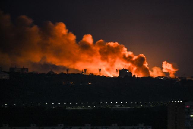 Smoke rises as the glow from fires light the sky during a Russian strike on the Ukrainian capital Kyiv on May 24, 2026, amid the Russian invasion in Ukraine. A large ballistic missile attack pounded Kyiv early on May 24, authorities said, wounding at least five people after Moscow threatened retaliation for strikes in Russian-occupied eastern Ukraine. (Photo by Evgen KOTENKO / AFP)