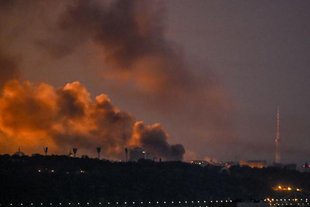 Smoke rises as the glow from fires light the sky during a Russian strike on the Ukrainian capital Kyiv on May 24, 2026, amid the Russian invasion in Ukraine. A large ballistic missile attack pounded Kyiv early on May 24, authorities said, wounding at least five people after Moscow threatened retaliation for strikes in Russian-occupied eastern Ukraine. (Photo by Evgen KOTENKO / AFP)