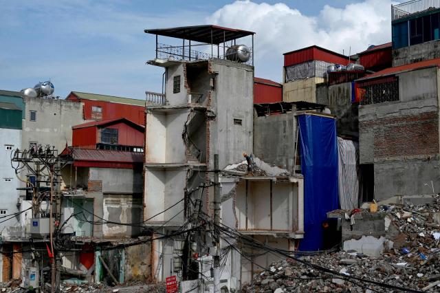 This photograph taken on May 20, 2026, shows a worker at a demolition site to make way for an expanded road network in Hanoi. Rows of townhouses torn down in hours, roads ripped up by bulldozers and city blocks reduced to rubble in the name of progress -- giant construction sites litter Hanoi as it races ahead with urban renewal. (Photo by Nhac NGUYEN / AFP) / To go with 'VIETNAM-ECONOMY-INFRASTRUCTURE-RIGHTS-HANOI,FOCUS' by Lam Nguyen and Ty McCormick