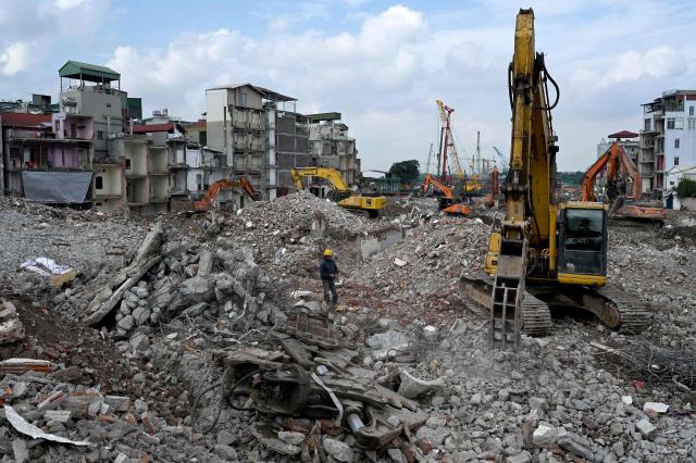 This photograph taken on May 20, 2026, shows a worker walking over debris of demolished residential buildings torn down to make way for an expanded road network in Hanoi. Rows of townhouses torn down in hours, roads ripped up by bulldozers and city blocks reduced to rubble in the name of progress -- giant construction sites litter Hanoi as it races ahead with urban renewal. (Photo by Nhac NGUYEN / AFP) / To go with 'VIETNAM-ECONOMY-INFRASTRUCTURE-RIGHTS-HANOI,FOCUS' by Lam Nguyen and Ty McCormick