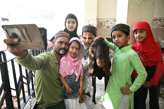 Muslim devotees take selfies with their goat after offering Eid al-Adha prayers at Jama Masjid Khairuddin in Amritsar on May 28, 2026. (Photo by Narinder NANU / AFP)