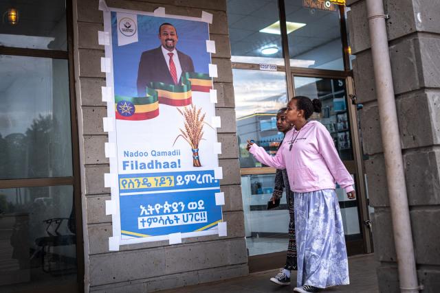 People walk past a poster of the political party of Prime Minister Abiy Ahmed, The Prosperity Party, on May 27, 2026 ahead of Ethiopia’s general elections scheduled for June 1, 2026. (Photo by Marco Simoncelli / AFP)