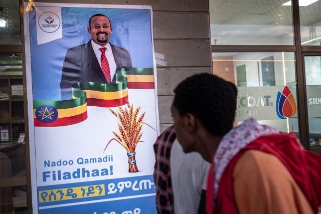People walk past an election campaign poster depicting Ethiopia’s Prime Minister Abiy Ahmed in Jimma on May 27, 2026 ahead of Ethiopia’s general elections scheduled for June 1, 2026. (Photo by Marco Simoncelli / AFP)