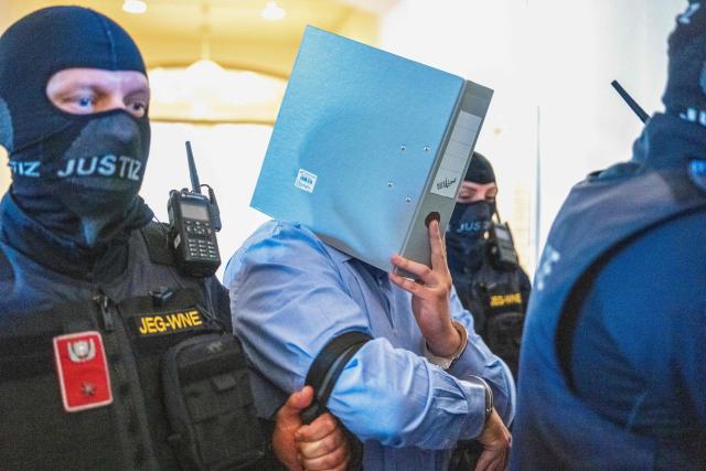 A 18-year-old defendant, who allegedly planned an attack on a Taylor Swift concert at the Ernst Happel Stadium in Vienna, hides behind a folder as Austrian justice guards guide them to the Regional Court of Wiener Neustadt in Wiener Neustadt, Lower Austria, on May 28, 2026. The court is expected to rule on May 28, 2026 in the trial of a 21-year-old man who has pleaded guilty to plotting a jihadist attack on a Taylor Swift concert. The three Vienna dates in the US megastar's record-breaking "Eras" tour were cancelled in the summer of 2024 after authorities warned of the plot. (Photo by Joe Klamar / AFP)