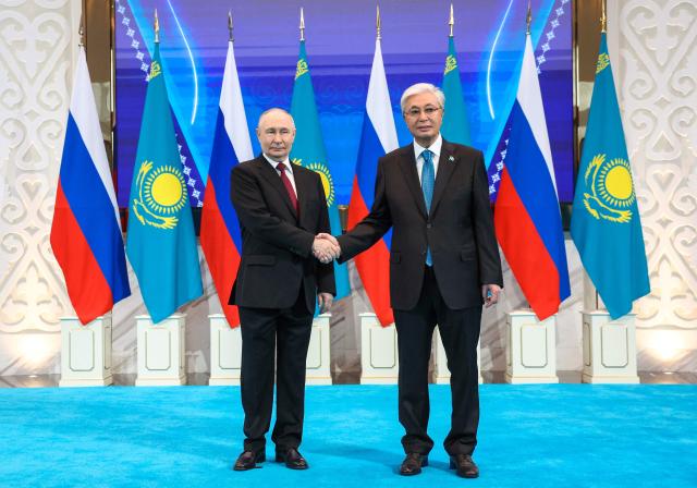 In this pool photograph distributed by the Russian state agency Sputnik Russian President Vladimir Putin (L) is welcomed by Kazakh President Kassym-Jomart Tokayev (R) at the Palace of Independence during Putin's state visit to Kazakhstan in Astana on May 27, 2026. (Photo by Alexander KAZAKOV / POOL / AFP)
