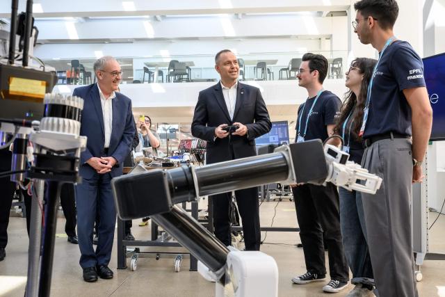 Poland's President Karol Nawrocki (C) holds a remote control beside Switzerland's President Guy Parmelin (L) as he interacts with students next to the Mars rover Polaris of the Xplore project during his visit at the Swiss Federal Institute of Technology of Lausanne (EPFL) in Ecublens on May 28, 2026. Nawrocki is on two-day state visit in Switzerland. (Photo by Fabrice COFFRINI / AFP)