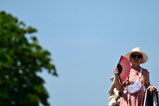 A spectator tries to cool off with a fan as she watches US Iva Jovic playing against US Emma Navarro during their women's singles match on day 5 of the French Open tennis tournament at the Roland-Garros Complex in Paris on May 28, 2026. (Photo by JULIEN DE ROSA / AFP)