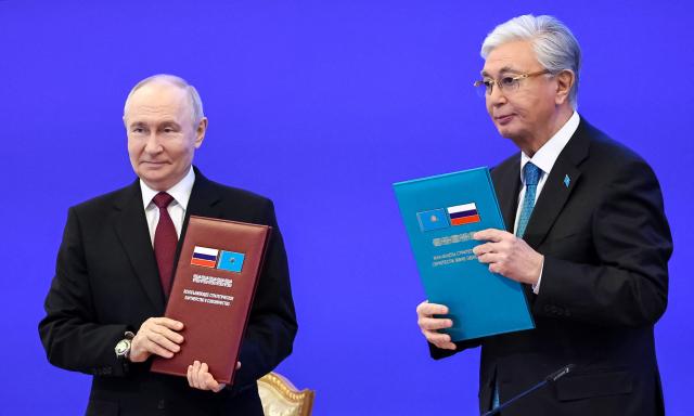 In this pool photograph distributed by the Russian state agency Sputnik Russian President Vladimir Putin (L) and Kazakh President Kassym-Jomart Tokayev pose as they exchange document folders during a ceremony at the Palace of Independence during Putin's state visit to Kazakhstan in Astana on May 28, 2026. (Photo by Alexander KAZAKOV / POOL / AFP)