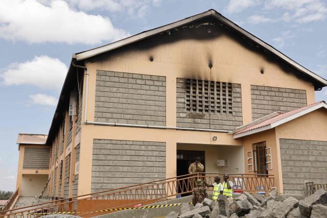 Kenyan police officers and forensic experts stand at the entrance of a building at Utumishi Girls Academy where a deadly fire took place in Nakuru, north of the capital Nairobi on May 28, 2026. A fire in a girls' dormitory in Kenya on May 28 killed 16 children and hospitalised 79 in the latest deadly blaze to hit a school in the east African country. The fire broke out shortly before 1:00 am local time at Utumishi Girls Academy in Nakuru County, around 120 kilometres (75 miles) north of the capital Nairobi, officials said. (Photo by SIMON MAINA / AFP)