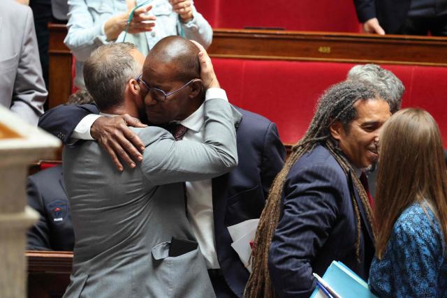 Libertes, Independants, Outre-Mer et Territoires' MP Max Mathiasin (C/R) embraces a fellow MP as his proposed bill aimed at abolishing the slavery-related laws passed unanimously at The National Assembly, France's lower house parliament, in Paris on May 28, 2026. These laws, known as Code Noir ("Black Code") classified enslaved people as "chattels" that could be acquired by a master in the same way as property, or established penalties for escapeincluding the cutting off of ears, branding with a lily, and even the death penalty. (Photo by Ludovic MARIN / AFP)