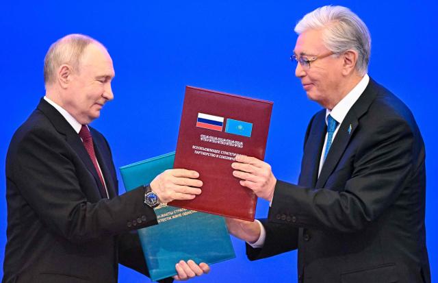 In this pool photograph distributed by the Russian state agency Sputnik Russian President Vladimir Putin (L) and Kazakh President Kassym-Jomart Tokayev exchange document folders during a ceremony at the Palace of Independence during Putin's state visit to Kazakhstan in Astana on May 28, 2026. (Photo by Alexander KAZAKOV / POOL / AFP)