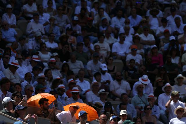 Spectators shield themselves from the sun on Court Philippe-Chatrier as they watch Italy's Jannik Sinner play against Argentina's Juan Manuel Cerundolo on day 5 of the French Open tennis tournament on Court Philippe-Chatrier at the Roland-Garros Complex in Paris on May 28, 2026. (Photo by Alain JOCARD / AFP)
