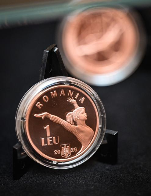 A copper-plated coin showing Romanian gymnastics legend Nadia Comaneci is on display at the National Bank of Romania (BNR) in Bucharest on May 28, 2026. The central bank launched a special numismatic issue—comprising gold, silver, and copper-plated tombac coins—to mark the 50th anniversary of Com?neci achieving the first-ever perfect 10.0 score in Olympic history at the Montreal 1976 Games. The reverse of the coins depicts her iconic uneven bars routine and the historic "1.00" scoreboard display. (Photo by Daniel MIHAILESCU / AFP)