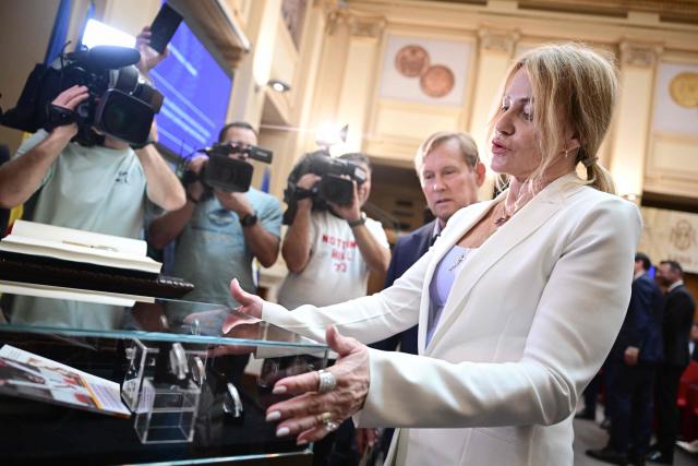 Romanian gymnastics legend Nadia Comaneci looks at he National Bank of Romania (BNR) in Bucharest on May 28, 2026. The central bank launched a special numismatic issue—comprising gold, silver, and copper-plated tombac coins—to mark the 50th anniversary of Com?neci achieving the first-ever perfect 10.0 score in Olympic history at the Montreal 1976 Games. The reverse of the coins depicts her iconic uneven bars routine and the historic "1.00" scoreboard display. (Photo by Daniel MIHAILESCU / AFP)