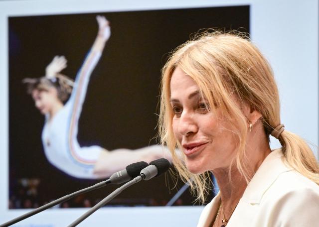 Romanian gymnastics legend Nadia Comaneci speaks during a ceremony at the National Bank of Romania (BNR) in Bucharest on May 28, 2026. The central bank launched a special numismatic issue—comprising gold, silver, and copper-plated tombac coins—to mark the 50th anniversary of Com?neci achieving the first-ever perfect 10.0 score in Olympic history at the Montreal 1976 Games. The reverse of the coins depicts her iconic uneven bars routine and the historic "1.00" scoreboard display. (Photo by Daniel MIHAILESCU / AFP)