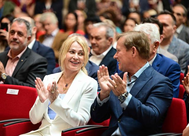 Romanian gymnastics legend Nadia Comaneci (L) and her husband Bart Conner (R) attend a ceremony at the National Bank of Romania (BNR) in Bucharest on May 28, 2026. The central bank launched a special numismatic issue—comprising gold, silver, and copper-plated tombac coins—to mark the 50th anniversary of Com?neci achieving the first-ever perfect 10.0 score in Olympic history at the Montreal 1976 Games. The reverse of the coins depicts her iconic uneven bars routine and the historic "1.00" scoreboard display. (Photo by Daniel MIHAILESCU / AFP)
