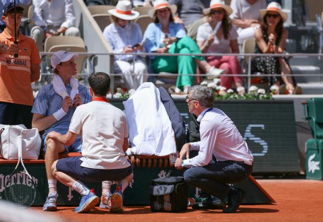 Italy's Jannik Sinner (2L) is treated by medical staff during his men's singles match against Argentina's Juan Manuel Cerundolo on day 5 of the French Open tennis tournament on Court Philippe-Chatrier at the Roland-Garros Complex in Paris on May 28, 2026. (Photo by Alain JOCARD / AFP)