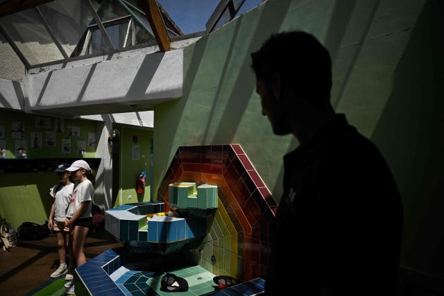 A man and children stand under the glass-roofed corridor of the Isle Verte primary school which closes its doors on May 28 and 29 afternoon after a heatwave pushed temperatures up to 53°C at the beginning of the week, in Soustons, south-western France, on May 28, 2026. Western Europe faced another day of record-breaking temperatures as a heatwave pushed the mercury well above normal levels for May. A so-called "heat dome" of warm air from northern Africa trapped under a high-pressure system over western Europe is behind the sort of heat not usually seen until high summer. (Photo by Philippe LOPEZ / AFP)