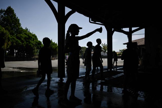 Children play with water to cool off in the playground of the Isle Verte primary school which closes its doors on May 28 and 29 afternoon after a heatwave pushed temperatures up to 53°C at the beginning of the week, in Soustons, south-western France, on May 28, 2026. Western Europe faced another day of record-breaking temperatures as a heatwave pushed the mercury well above normal levels for May. A so-called "heat dome" of warm air from northern Africa trapped under a high-pressure system over western Europe is behind the sort of heat not usually seen until high summer. (Photo by Philippe LOPEZ / AFP)