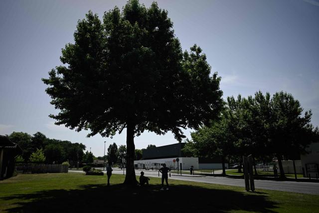 Parents wait under a tree outside the Isle Verte primary school which closes its doors on May 28 and 29 afternoon after a heatwave pushed temperatures up to 53°C at the beginning of the week, in Soustons, south-western France, on May 28, 2026. Western Europe faced another day of record-breaking temperatures as a heatwave pushed the mercury well above normal levels for May. A so-called "heat dome" of warm air from northern Africa trapped under a high-pressure system over western Europe is behind the sort of heat not usually seen until high summer. (Photo by Philippe LOPEZ / AFP)