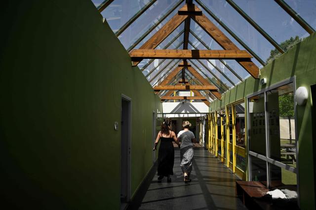 Women walk under the glass-roofed corridor of the Isle Verte primary school which closes its doors on May 28 and 29 afternoon after a heatwave pushed temperatures up to 53°C at the beginning of the week, in Soustons, south-western France, on May 28, 2026. Western Europe faced another day of record-breaking temperatures as a heatwave pushed the mercury well above normal levels for May. A so-called "heat dome" of warm air from northern Africa trapped under a high-pressure system over western Europe is behind the sort of heat not usually seen until high summer. (Photo by Philippe LOPEZ / AFP)