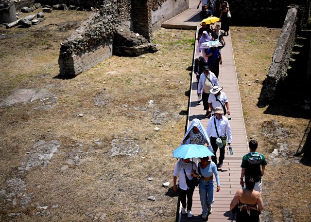 People shield themselves from the sun with umbrellas as they visit the Forum during an early-season heatwave in Rome on May 28, 2026.  (Photo by Tiziana FABI / AFP)