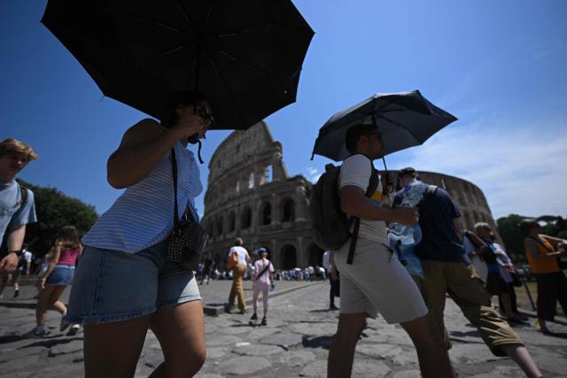 People shield themselves from the sun with umbrellas near the Colosseum during an early-season heatwave in Rome on May 28, 2026.  (Photo by Tiziana FABI / AFP)