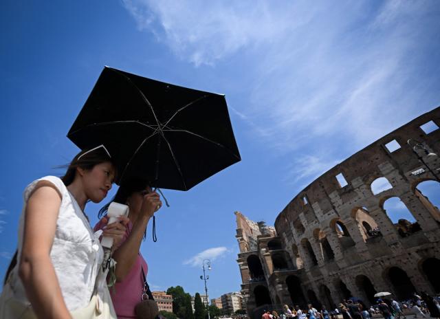 People shield themselves from the sun with an umbrella near the Colosseum during an early-season heatwave in Rome on May 28, 2026.  (Photo by Tiziana FABI / AFP)