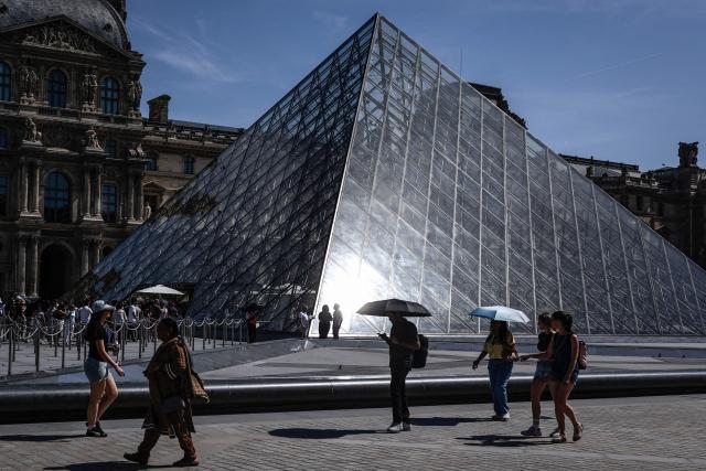 Tourists walk past the Louvre Museum in Paris on May 28, 2026, as a heatwave hits France. French weather service Météo-France placed the capital under yellow alert amid an exceptionally early heatwave, with temperatures forecast to reach 35C across the region. (Photo by STEPHANE DE SAKUTIN / AFP)