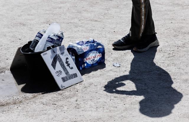 A street vendor seels bottles of water outside the Louvre Museum in Paris on May 28, 2026, as a heatwave hits France. French weather service Météo-France placed the capital under yellow alert amid an exceptionally early heatwave, with temperatures forecast to reach 35C across the region. (Photo by STEPHANE DE SAKUTIN / AFP)