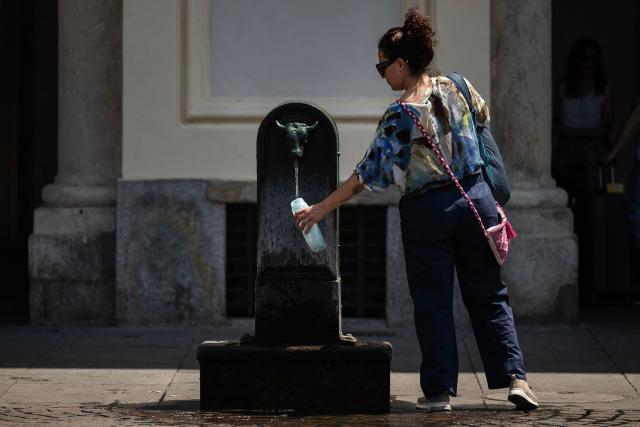 A tourist fills a bottle with water at a public fountain in Piazza San Carlo  in Turin, northwestern Italy, during an early-season heatwave in Europe, on May 28, 2026. (Photo by MARCO BERTORELLO / AFP)