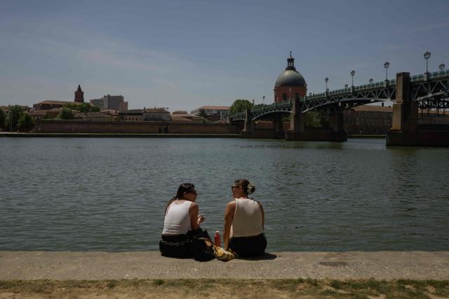 Women sit on the banks of the River Garonne in Toulouse, southwestern France, on May 28, 2026 as a heatwave hits France. Western Europe faced another day of record-breaking temperatures as a heatwave pushed the mercury well above normal levels for May. A so-called "heat dome" of warm air from northern Africa trapped under a high-pressure system over western Europe is behind the sort of heat not usually seen until high summer. (Photo by Ed JONES / AFP)