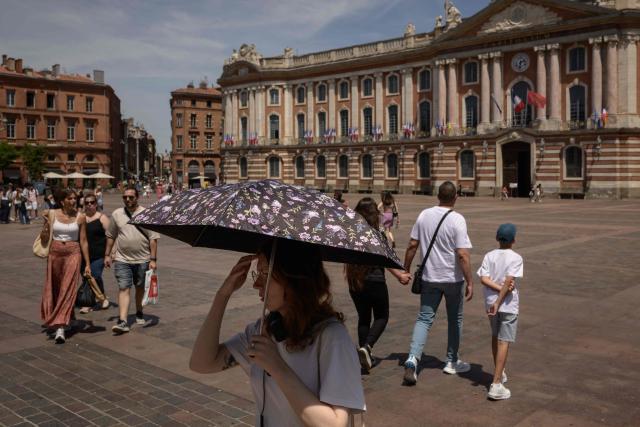 A woman shelters from the sun under a parasol as pedestrians walk through the Capitol square in Toulouse, southwestern France, on May 28, 2026 as a heatwave hits France. Western Europe faced another day of record-breaking temperatures as a heatwave pushed the mercury well above normal levels for May. A so-called "heat dome" of warm air from northern Africa trapped under a high-pressure system over western Europe is behind the sort of heat not usually seen until high summer. (Photo by Ed JONES / AFP)