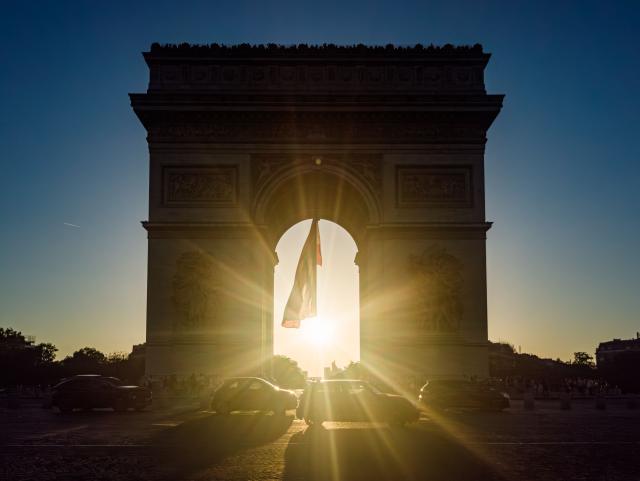 The sun sets behind the Arc de Triomphe monument in Paris as a record-breaking early heatwave scorches a swathe of western Europe on May 27, 2026. The UK and France have reported their hottest ever May days this week as a "heat dome" brought sizzling temperatures more typical of midsummer to western Europe. (Photo by Laurent EMMANUEL / AFP)