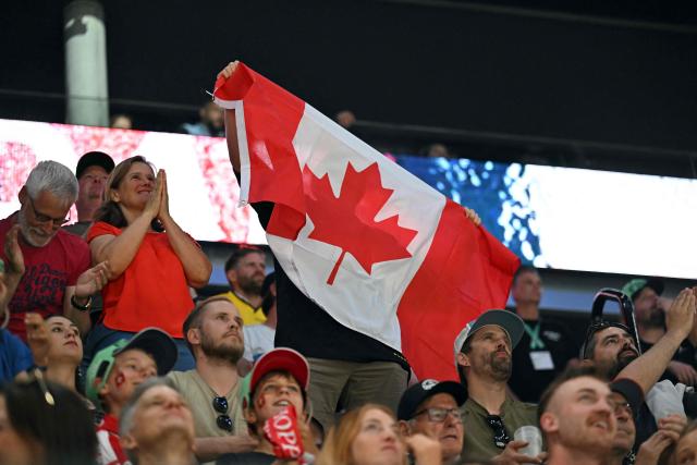 A Canada fan waves the country's flag to celebrate the team's first goal during the IIHF Ice Hockey Men's World Championship quarter-final match between Canada and USA in Fribourg, Switzerland on May 28, 2026. (Photo by Fabrice COFFRINI / AFP)