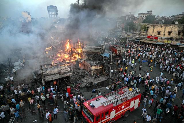 People gather around a fire that broke out at a bamboo market in Amritsar on May 28, 2026. (Photo by Narinder NANU / AFP)
