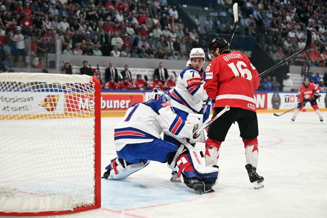 USA's goalkeeper #1 Devin Cooley (L), USA's defender #7 Ryan Ufko (C) and Canada’s forward #16 Connor Brown vie for the puck during the IIHF Ice Hockey Men's World Championship quarter-final match between Canada and USA in Fribourg, Switzerland on May 28, 2026. (Photo by Fabrice COFFRINI / AFP)