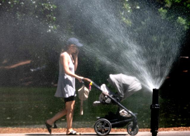 A woman pushes a stroller past a water sprinkler at the City park (Stadtpark) on a sunny and hot day in Vienna, Austria, on May 28, 2026. Starting in late May, parts of Europe have been affected by heatwaves, breaking records in Spain, the United Kingdom, Germany, France, Ireland. (Photo by Joe Klamar / AFP)