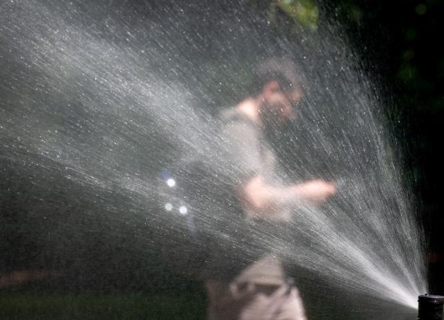 A man walks past a water sprinkler at the City park (Stadtpark) on a sunny and hot day in Vienna, Austria, on May 28, 2026. Starting in late May, parts of Europe have been affected by heatwaves, breaking records in Spain, the United Kingdom, Germany, France, Ireland. (Photo by Joe Klamar / AFP)