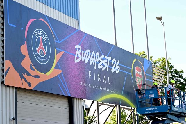 Workers put up a giant UEFA Champions League final poster at the Puskas Arena on May 28, 2026 ahead of the UEFA Champions League in Budapest on May 28, 2026. The stadium, named after Hungary's most famous footballer Ferenc Puskas, will host the Champions League final between Paris Saint-Germain (PSG) and Arsenal on May 30, 2026. (Photo by Attila KISBENEDEK / AFP)