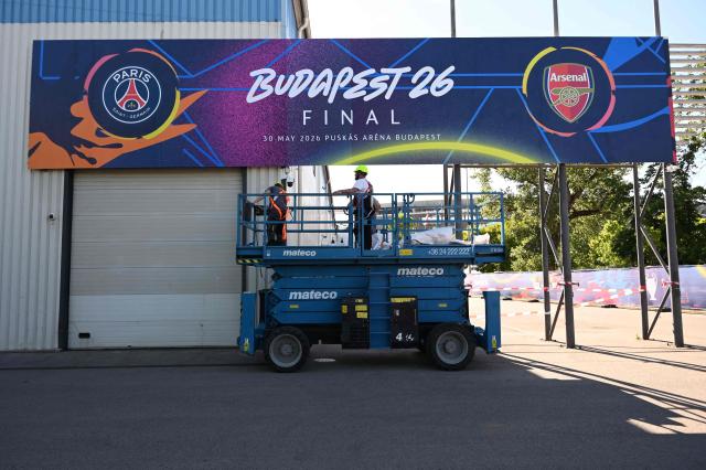 Workers put up a giant UEFA Champions League final poster at the Puskas Arena on May 28, 2026 ahead of the UEFA Champions League in Budapest on May 28, 2026. The stadium, named after Hungary's most famous footballer Ferenc Puskas, will host the Champions League final between Paris Saint-Germain (PSG) and Arsenal on May 30, 2026. (Photo by Attila KISBENEDEK / AFP)