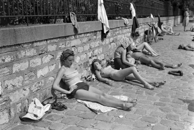 (FILES) People rest on the banks of the Seine river on June 5, 1950, during a heat wave in Paris. (Photo by AFP)
