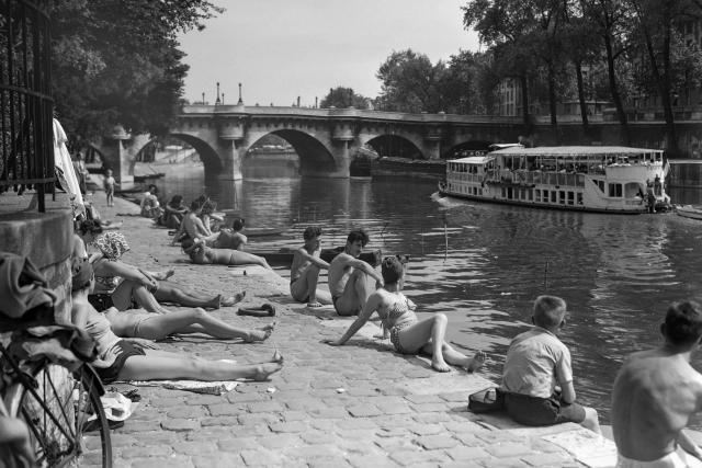 (FILES) People rest on the banks of the Seine river on June 5, 1950, during a heat wave in Paris. (Photo by AFP)