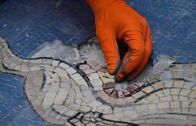 Restorer Gianluca Galli works on the mosaic of the bull during the restoration in the Galleria Vittorio Emanuele II, donwtown Milan, on May 28, 2026. "Because of constant pirouettes on the heel made by tourists visiting Milan, the pink tesserae that make up its testicles have been worn down, forming a small crater," city authorities said in a statement. The beige bull mosaic representing Turin, the then capital of Italy, is part of the flooring in the 19th century shopping arcade near Milan's famous Duomo cathedral. (Photo by Stefano RELLANDINI / AFP)